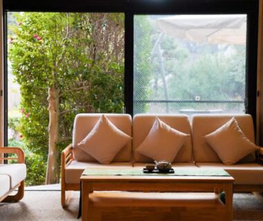 Wooden sofa with beige cushions facing a large window overlooking garden at Waseidō Zen, Hyōgo