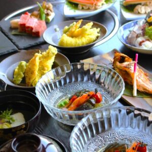 Assorted small Japanese dishes including sashimi, tempura and grilled fish in a ryokan dining setting in Kyoto