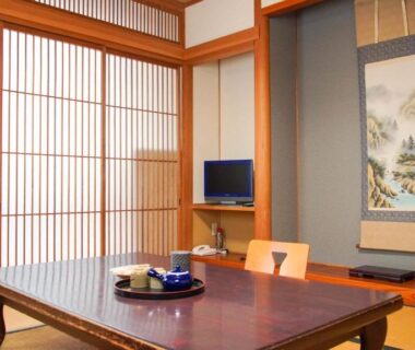 Traditional tatami room with low wooden table, shoji screens, hanging scroll and tea set at Ryokan Ōmasa, Saga