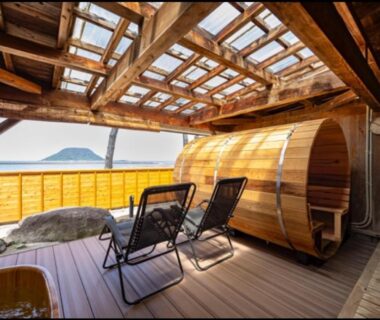 Outdoor wooden barrel bath with deck chairs overlooking sea at Ryokan Ōmasa, Saga, Kyushu