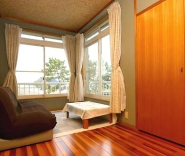 Low lounge chair, small table and wooden wardrobe in a bay window room at Ryokan Ōmasa, Saga