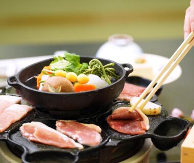 Chopsticks holding grilled meat over tabletop grill with simmering hotpot, Hôtel touristique Tōnomine, Nara, Kansai