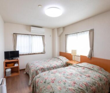 Twin beds with floral bedspreads at Shirakawagō no Yu in Gifu, Chūbu, Japan