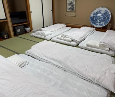 Traditional tatami room with multiple futon beds, shoji doors and low shelving at Shirakawagō no Yu in Gifu