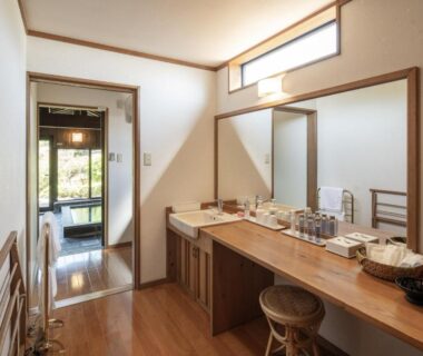 Long wooden vanity with mirrors and stools opening to tatami room and garden view at Sansō Hanayu in Kumamoto