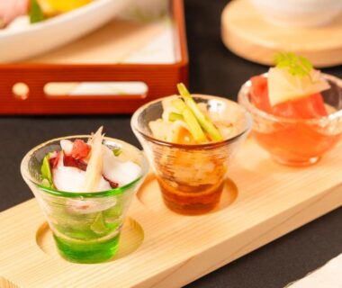 Three small glass bowls with colorful appetizers on a wooden tray served at 奥州平泉温泉旅館 itsumu in Iwate