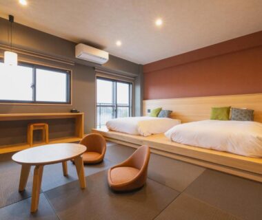 Raised tatami sleeping area with twin beds, low table and floor chairs at 奥州平泉温泉旅館 itsumu, Iwate Tōhoku