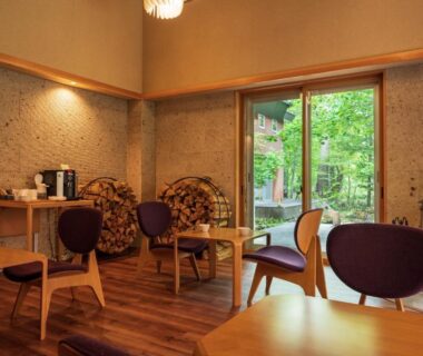 Cozy wooden lounge with low tables and chairs opening to a garden at Yunomori Okunikko Yumoto Onsen, Tochigi