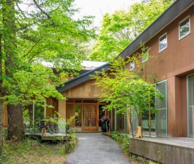 Walkway to wooden ryokan entrance surrounded by green trees at Yunomori Okunikko Yumoto Onsen, Tochigi