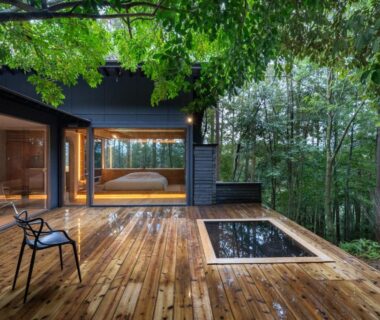Wooden terrace with sunken bath, glass-walled room and forest backdrop at Kaze no Mori, Saga