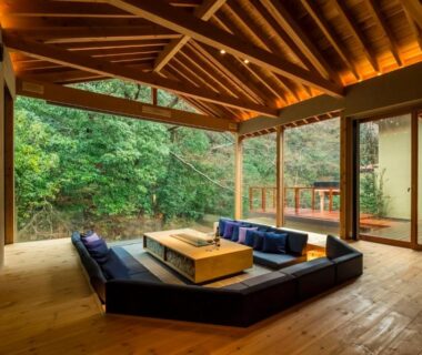 Open wooden lounge with low seating at Okuyugawara YUI overlooking forest in Kanagawa