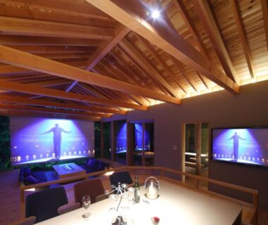 Interior with exposed wooden beams, low dining table and lounge screens at Okuyugawara YUI in Kanagawa Japan