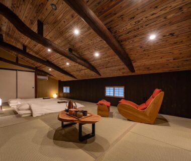 Spacious tatami room with futons, low table and wooden ceiling beams at Wabi Sabi ryokan in Himeji, Hyōgo