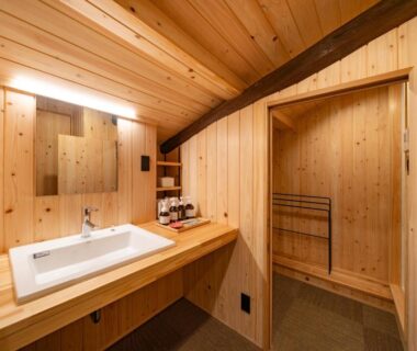 Wood-lined vanity with sink and mirror inside Wabi Sabi ryokan bathroom in Himeji, Hyōgo, Japan