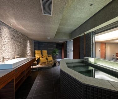 Tiled indoor onsen bath with loungers and textured stone wall at Kotan Ureshino, Ureshino Onsen, Saga