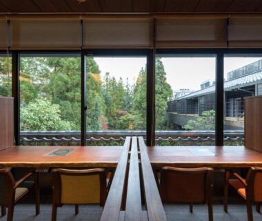 Long wooden dining table and chairs facing garden through floor-to-ceiling windows at Kotan Ureshino, Saga, Kyushu