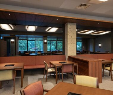 Calm ryokan dining room with wooden tables, cushioned chairs and large windows overlooking greenery at Kotan Ureshino in Saga