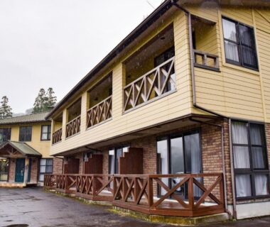 Two-story ryokan exterior with wooden verandas and large windows at Yasuragi no Sato Yamakuni in Ōita, Kyūshū
