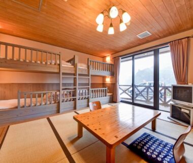 Japanese tatami room with bunk beds, low wooden table, balcony sliding doors at Yasuragi no Sato Yamakuni in Ōita