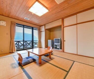 Tatami room with low table, zabuton cushions and balcony railing at Yasuragi no Sato Yamakuni, Ōita