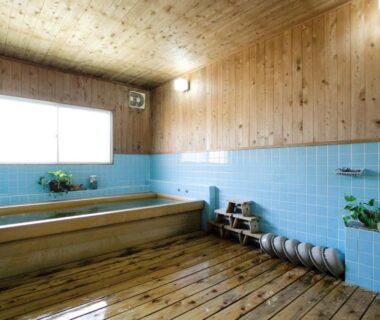 Indoor wooden bath with blue tile walls, stools and window at Awa Resort Ryokan Rinkai Garyū, Chiba