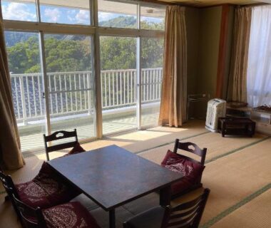 Tatami room with low table, cushions and balcony overlooking wooded hillside at Awa Resort Rinkai Chiba
