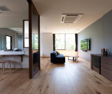 Spacious hardwood-floored guest room with lounge chair, vanity sink and sliding partition at IBUKU Miyajima, Hiroshima