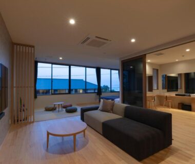 Spacious modern lounge with sofa, low table and large windows overlooking water at Miyajima Hanare no Yado IBUKU