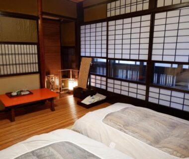 Twin beds in a traditional room with shoji screens, low table and wooden flooring at Sawashoku in Kyoto