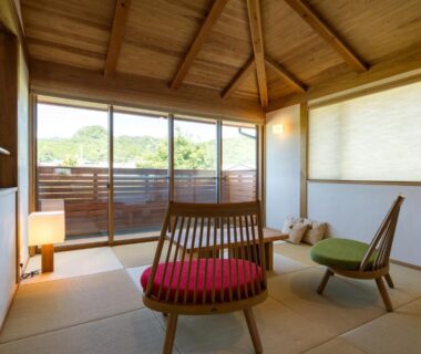 Tatami room with low wooden chairs, vaulted ceiling and sliding doors opening to a balcony at Shukubō Shingetsu, Saga