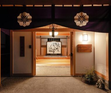 Illuminated traditional entrance with noren, wooden frame and tatami interior at 宿坊 観音院 Temple Hotel Kannonin in Gunma