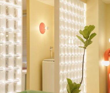 Softly lit lounge with illuminated wall panels, potted plant and sculptural floor lamp at TORA HOTEL Okachimachi