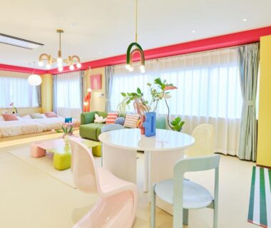 Bright pastel-hued guest room with platform beds, round dining table and large windows at TORA HOTEL Okachimachi Tokyo