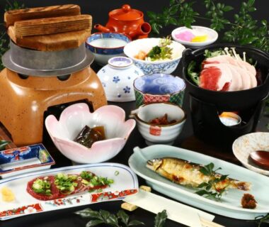 Assorted small dishes with grilled fish, soup pot, rice bowl and condiments arranged for a ryokan dinner