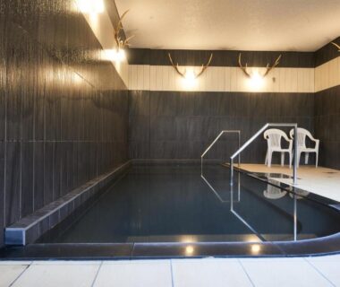 Indoor tiled onsen bath with handrail and seating at Hôtel Kumoi, Sōunkyō Onsen, Hokkaidō