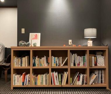 Low bookshelf with books and lamp in ryokan lounge at Hôtel Kumoi, Sōunkyō Onsen, Hokkaidō