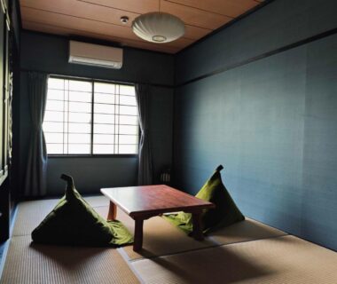 Traditional tatami room with low wooden table and triangular floor cushions by shoji window in Sōunkyō Onsen, Hokkaidō