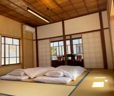 Traditional tatami room with folded futons, shoji screens and wooden ceiling at Yamashiroya Resort, Nagano