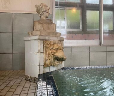 Tiled indoor bathing pool with decorative lion head water spout and windows at Yamashiroya Resort in Nagano