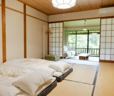 Traditional tatami room with folded futons, shoji screens and balcony overlooking lush greenery at Syaranoki Ōita