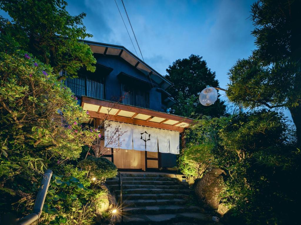 Lantern-lit entrance at 巛-sen-Yugawara Kanagawa Stone steps lead to lantern-lit noren entrance framed by garden foliage at 巛-sen-Yugawara ryokan in Kanagawa