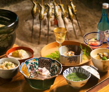 Assorted bowls and skewered grilled river fish with sake bottles, Wadaya ryokan, Chūbu Ishikawa