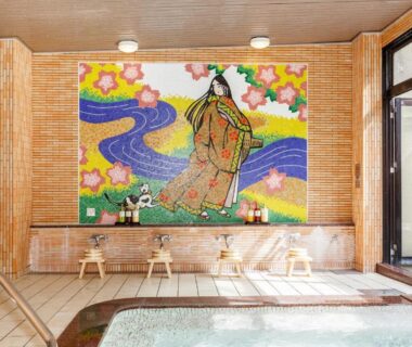 Indoor bathing area with mosaic artwork and wooden stools at Shikibu no Yakata Izutsuya in Fukushima