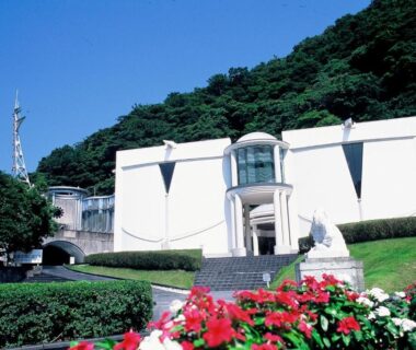 White modern ryokan building with flower beds and hillside backdrop at Oyado Shinshima in Shizuoka Chūbu