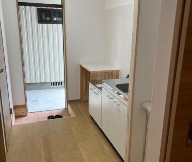 Genkan entrance with wooden floor, compact kitchenette and shoe storage at Oyado Daikonya in Kumamoto, Kyushu