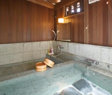 Stone indoor onsen bath with wooden walls and wooden buckets at Oyado Daikonya in Kumamoto, Kyūshū