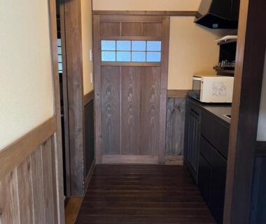 Genkan with raised wooden step and kitchenette by paneled door at Oyado Daikonya, Kumamoto, Kyūshū
