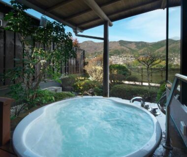Circular outdoor soaking tub on wooden deck at Oyado Zuiyō with river and mountain view in Shizuoka
