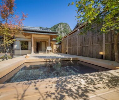 Outdoor soaking bath with tiled edge, wooden fence and ryokan entrance at Oyado Chikurintei, Saga