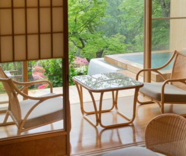 Tatami room with low table, wicker chairs and shoji screens opening to lush garden view